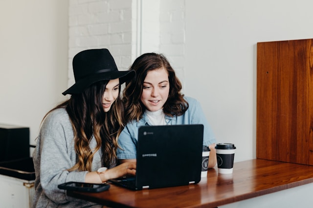 Two people leaning into a laptop together